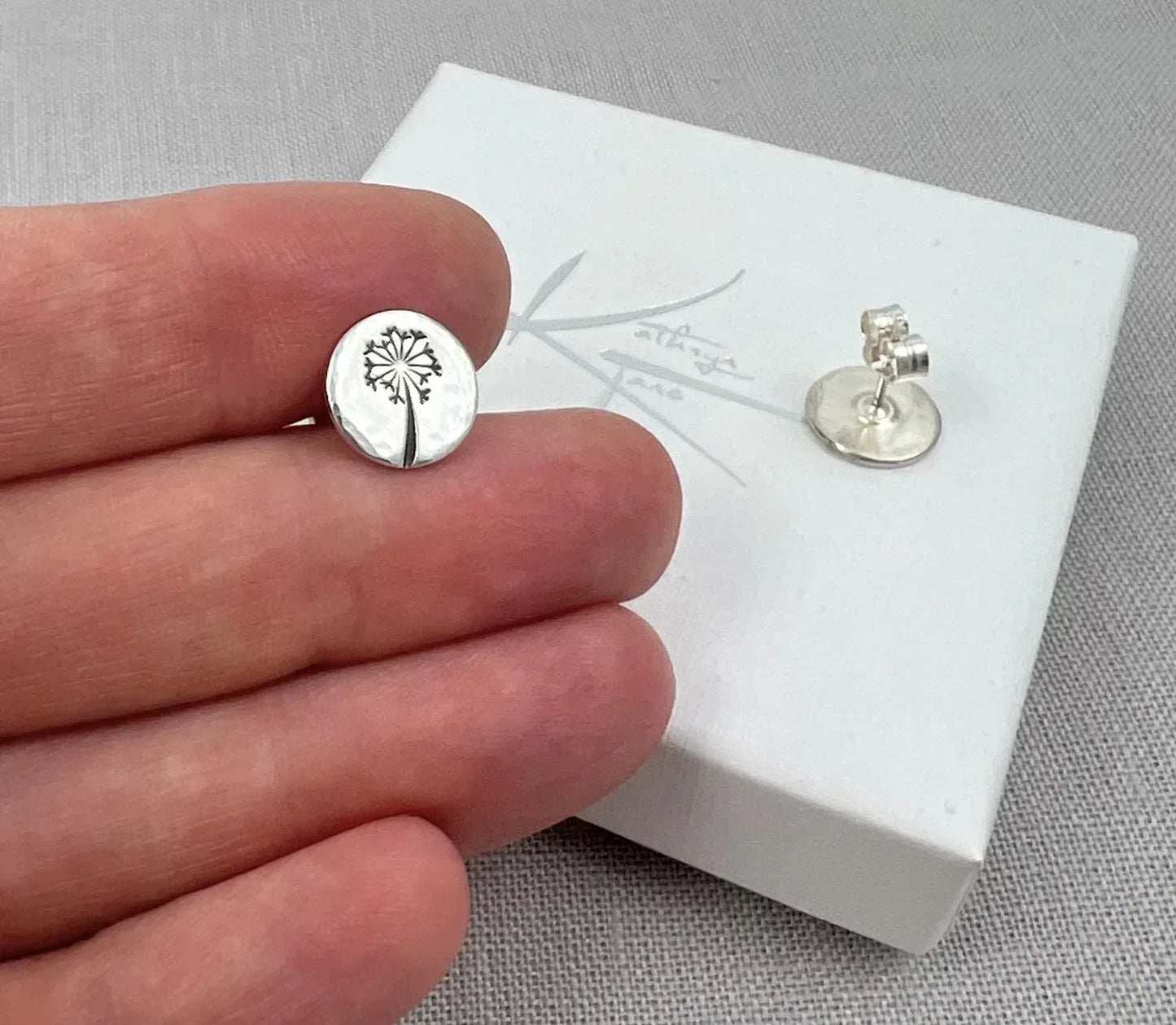 Sterling silver dandelion stud earrings on display box, round hammered design