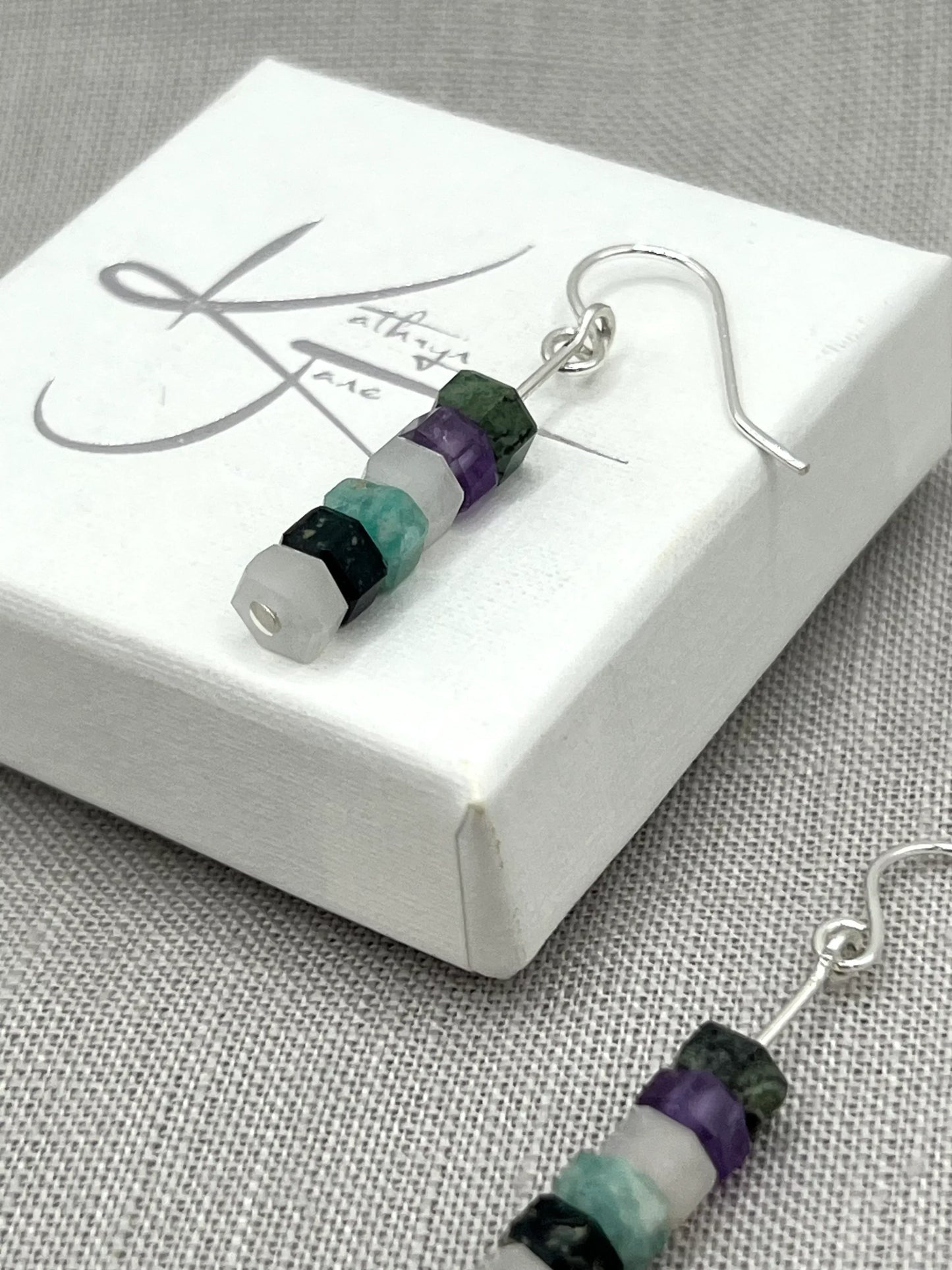 Dangle earrings with stacked purple, aqua, green, and white gemstone beads on silver hooks
