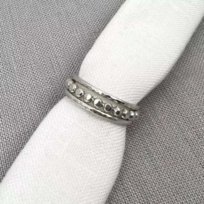 Silver textured stacking ring with beaded design on white fabric background