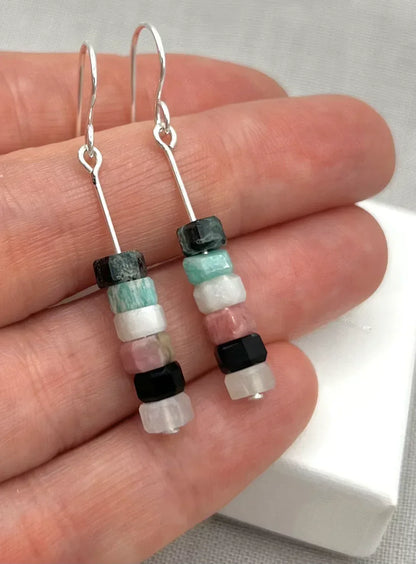 Hand holding dangle earrings with stacked aqua, pink, black and white stone beads