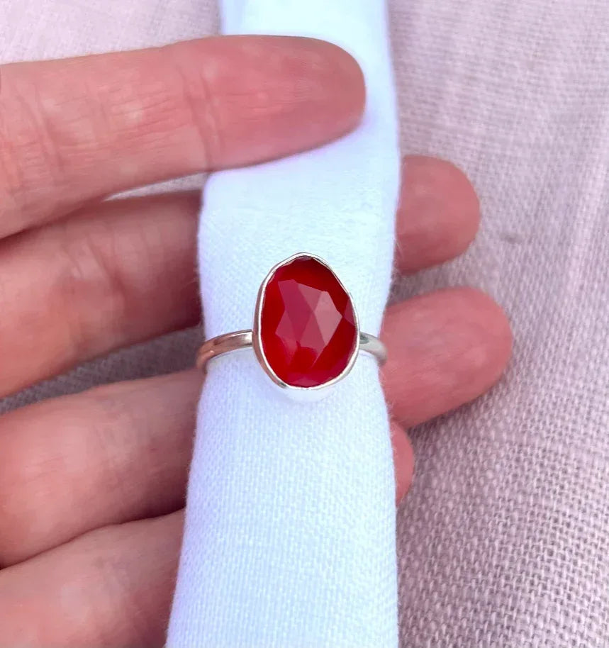 Handcrafted silver ring with faceted orange gemstone on light fabric background