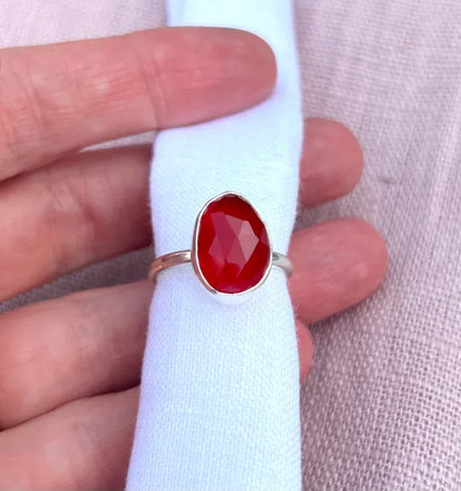 Handcrafted silver ring with faceted orange gemstone on light fabric background