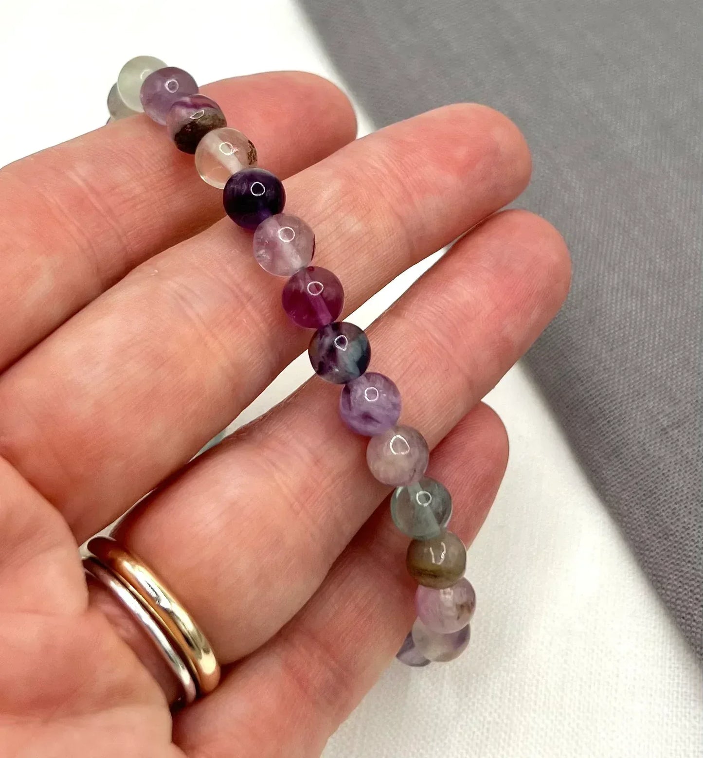 Hand holding round multicolor fluorite gemstone beads for jewelry making