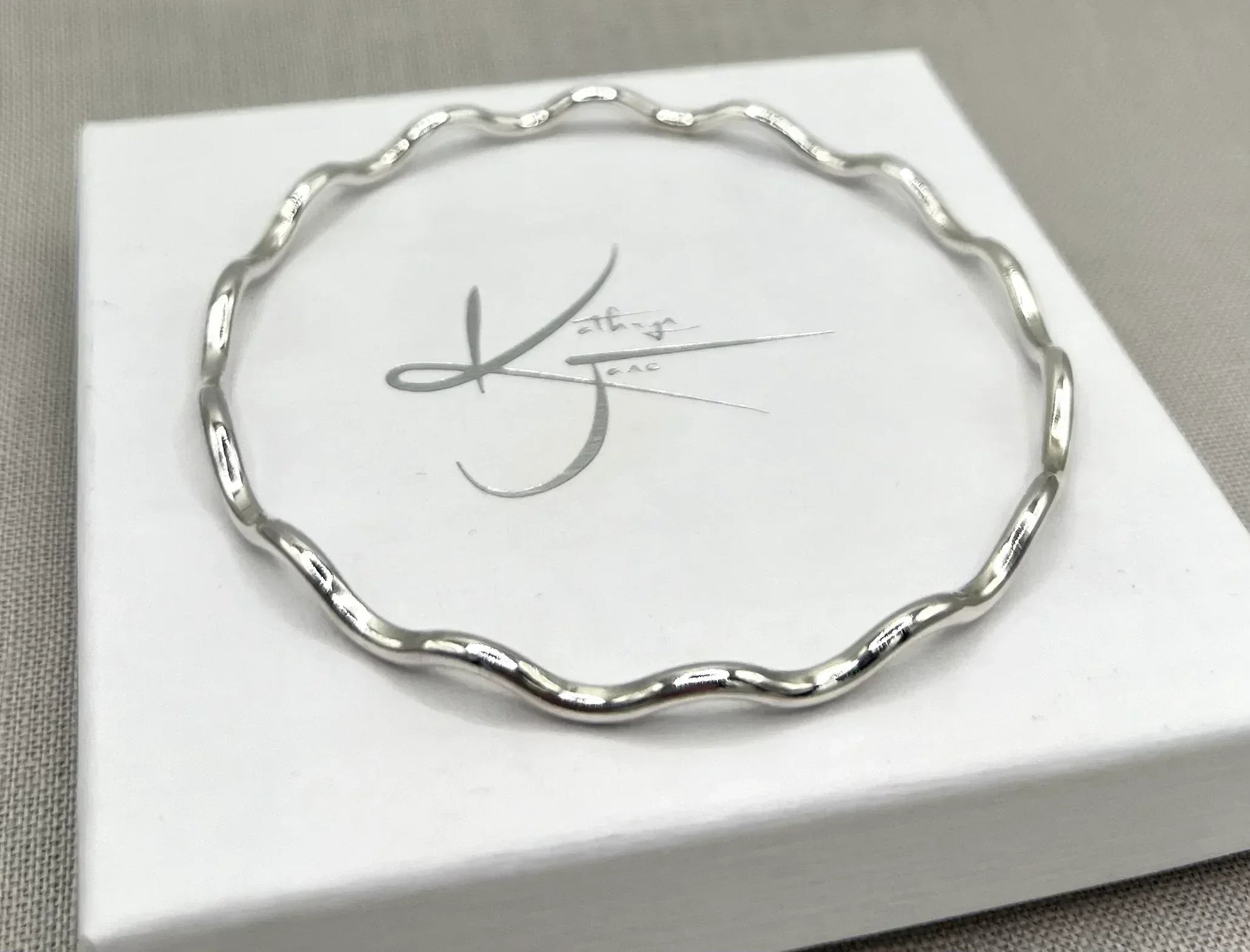Silver wavy bangle bracelet with a 2.5mm thickness on a white jewelry box