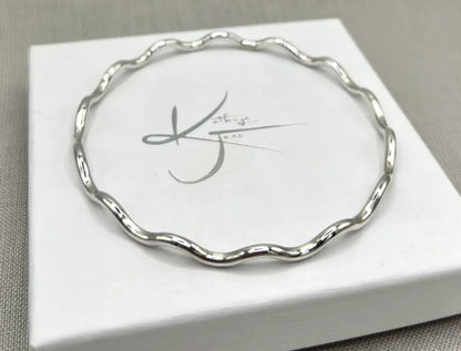 Silver wavy bangle bracelet with a 2.5mm thickness on a white jewelry box