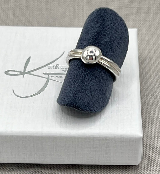 Silver ring on a navy blue ring cushion with a white box underneath