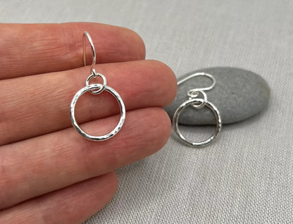 Handmade silver interlinked hoop earrings with hammered texture, displayed on fabric