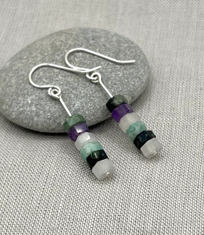 Silver hook earrings with stacked purple, aqua, and stone beads on a grey fabric background