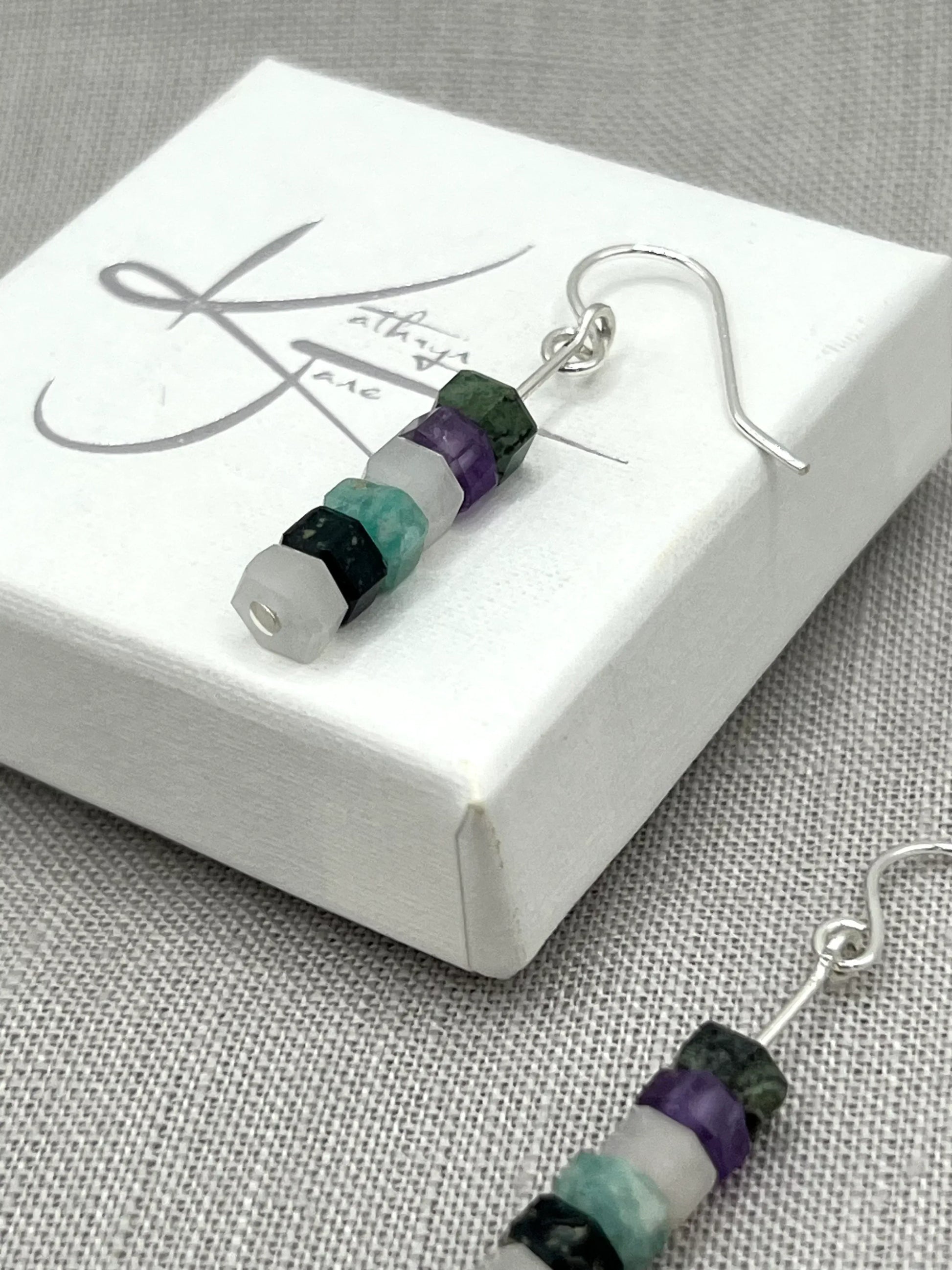 Dangle earrings with stacked purple, aqua, green, and white gemstone beads on silver hooks