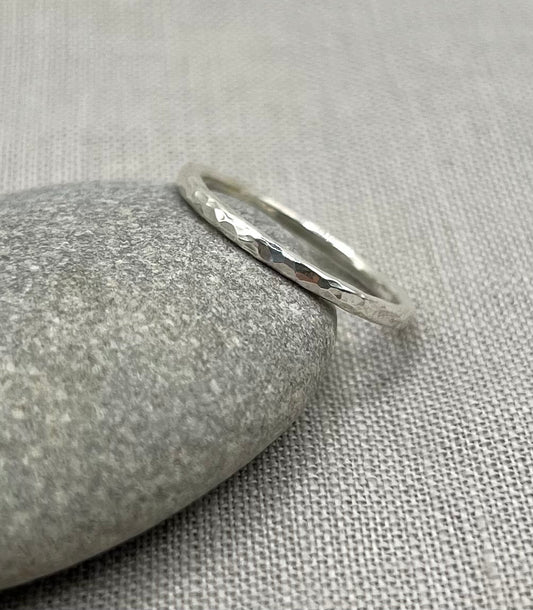 Silver ring with a textured surface on a gray stone