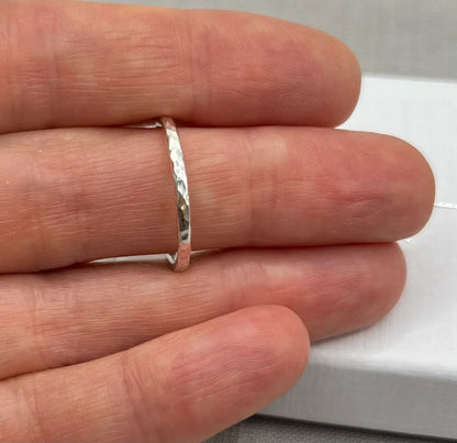 Hand holding a thin hammered silver textured stacker ring