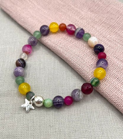 Multicolored beaded bracelet with a star charm on a light gray surface.