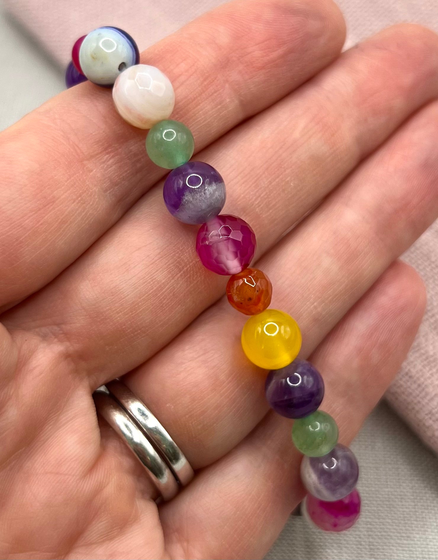 Colorful beaded bracelet on a hand with a plain background