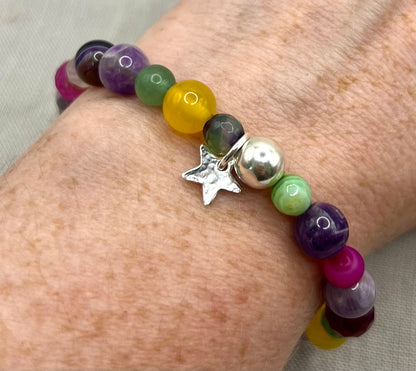 Multicolored beaded bracelet with a star charm on a wrist against a neutral background
