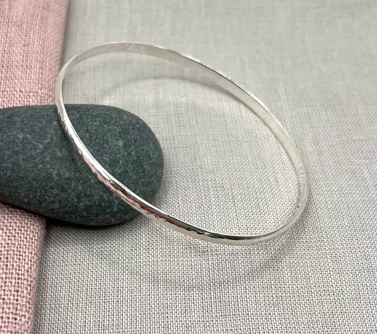 Silver bangle on a textured fabric background