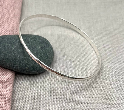 Silver bangle on a textured fabric background